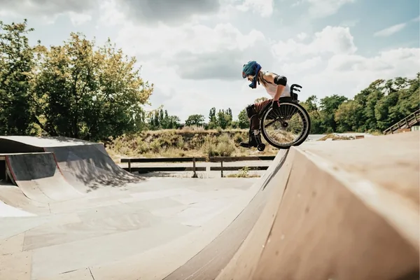 Sportler im Rollstuhl fährt eine Rampe in einem Skatepark