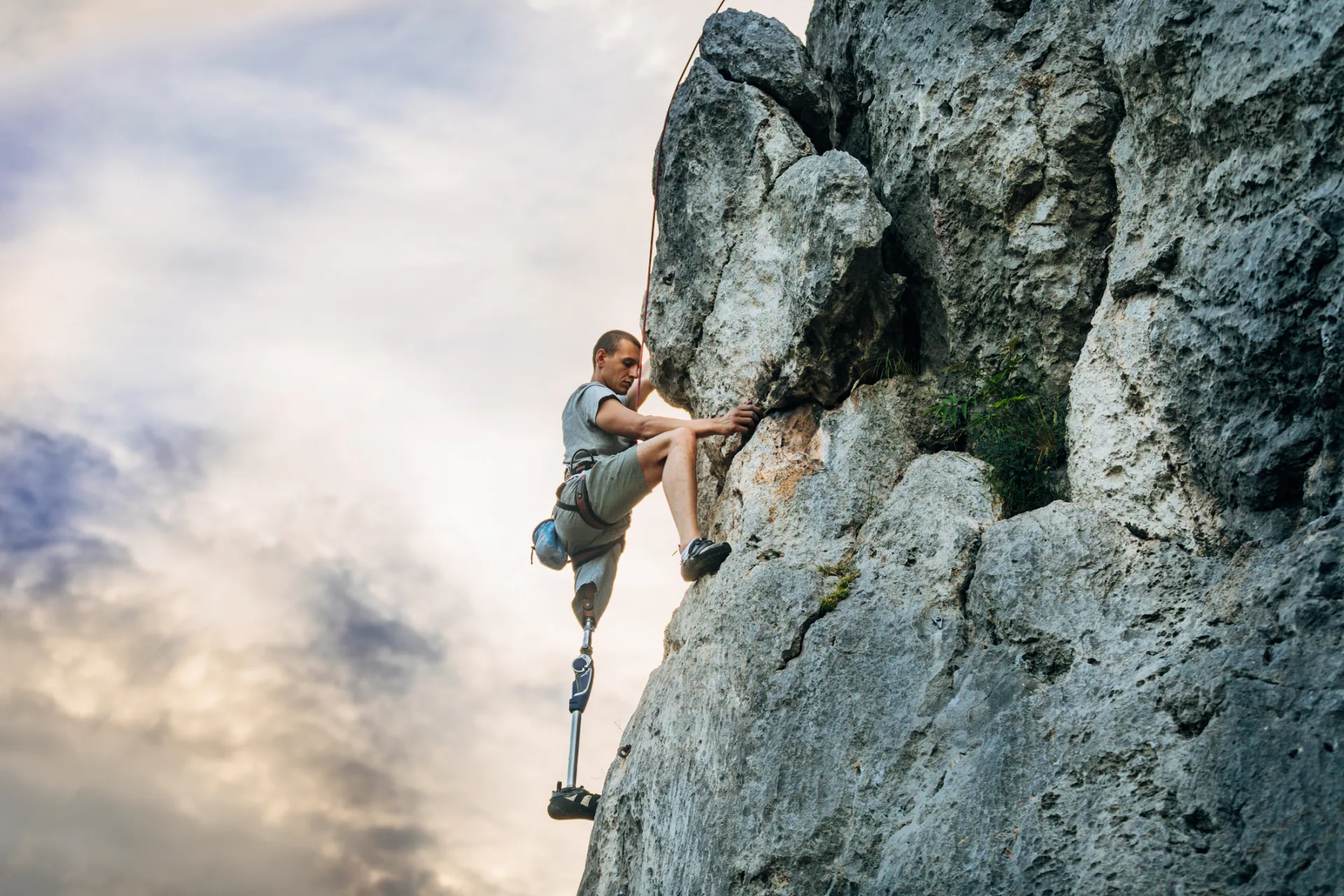 Kletterin mit Beinprothese an einer Felswand